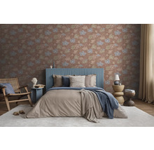 Vliestapete mit floralem Muster in einem modern eingerichteten Schlafzimmer mit gepolstertem Bett, Holzsessel und hellen Textilien.