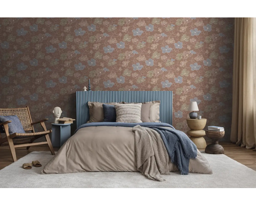 Vliestapete mit floralem Muster in einem modern eingerichteten Schlafzimmer mit gepolstertem Bett, Holzsessel und hellen Textilien.
