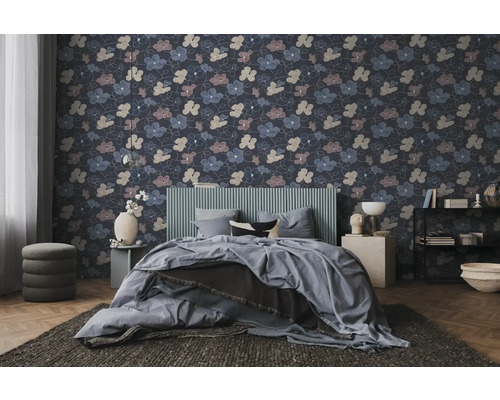 Vliestapete mit floralem Muster in einem modern eingerichteten Schlafzimmer mit grauem Bett und dunklem Teppich.