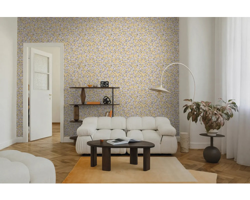 Wohnzimmer mit gelber Blättermuster-Tapete, weißem Polstersofa, dunklem Couchtisch und Fischgrätparkett. Helle und moderne Einrichtung.
