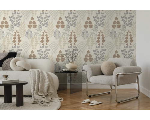 Helle Vliestapete mit botanischem Blättermuster in einem modern eingerichteten Wohnzimmer mit Sofa, Sessel und Parkettboden. Hell und aufgeräumt.