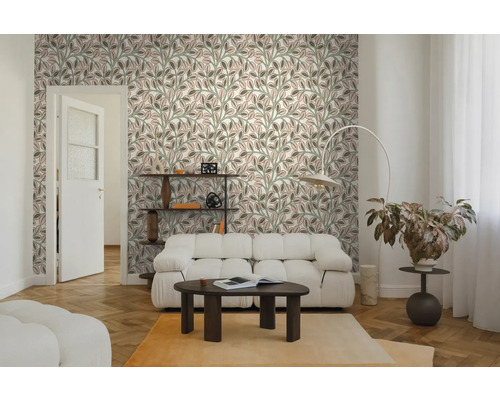 Helles Wohnzimmer mit Vliestapete im Blättermuster, weißem Sofa, dunklem Couchtisch und Fischgrätenparkett.