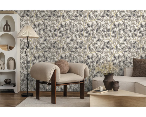 Vliestapete mit stilisiertem Blättermuster in einem modern eingerichteten Wohnzimmer mit Sessel, Stehlampe und Regal.