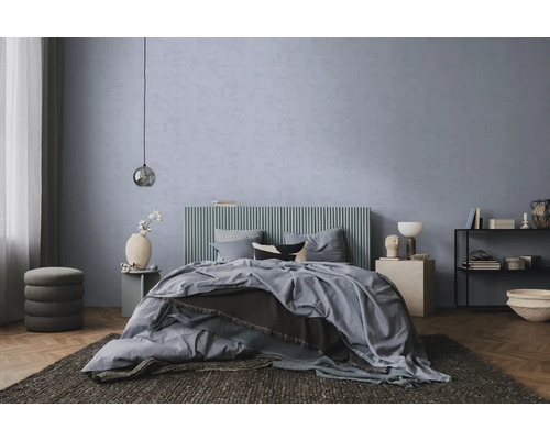 Modernes Schlafzimmer mit blau-grauer Strukturwand, Bett mit geripptem Kopfteil, Parkettboden und dunklem Teppich.