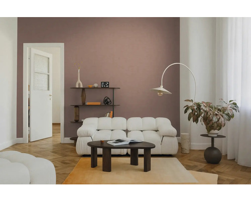 Modernes Wohnzimmer mit weißem Modulsofa, dunklem Couchtisch aus Holz und einer Bogenstehleuchte vor einer altrosa Wand.