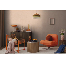 Modern eingerichtetes Wohnzimmer mit orangefarbenem Drahtsessel, Polstersessel, dunklem Sideboard und rundem Holzbeistelltisch vor hellgrauer Wand.