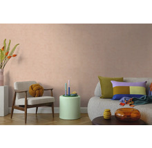Modernes Wohnzimmer mit strukturierter Wandfarbe in Pfirsich, Sessel, Sofa und farbenfroher Dekoration.