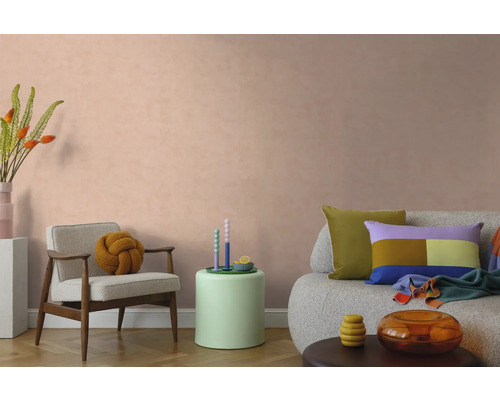 Modernes Wohnzimmer mit strukturierter Wandfarbe in Pfirsich, Sessel, Sofa und farbenfroher Dekoration.