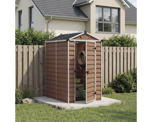 Kleines Gerätehaus in Holzoptik mit Satteldach, offener Tür mit Gartenzubehör, auf Betonfundament im Garten neben einem Holzzaun.