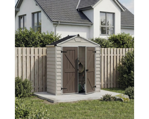 Kompaktes Gerätehaus aus Kunststoff mit Satteldach und geöffneter Doppeltür auf einer Betonplatte im Garten vor einem Holzzaun.