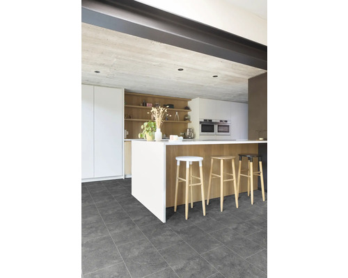 Moderne Küche mit dunkelgrauen Bodenfliesen in Steinoptik, weißer Kücheninsel mit Holzverkleidung und Barhockern aus Holz.