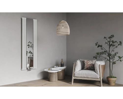 Vertikaler Design-Heizkörper mit integriertem Spiegel in einem hellen, modernen Wohnzimmer mit Sessel, Beistelltischen und einer Zimmerpflanze.