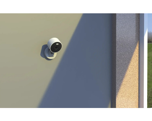 Weiße Außenüberwachungskamera an einer Fassade montiert, magnetische Halterung, modernes rundes Design.