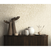 Strukturierte Tapete mit vertikalem Muster in Beige hinter einem dunklen Sideboard mit Dekorationsobjekten und Skulpturen.