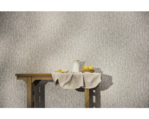 Vliestapete mit abstraktem, vertikalem Muster an einer Wand hinter einem Holztisch mit Krug und Zitronen.