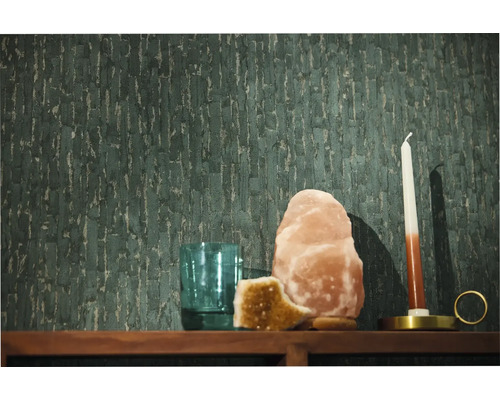 Dunkelgrüne strukturierte Vliestapete mit vertikalem Muster auf einer Wand hinter einem Holzregal mit Salzlampe Kerze und einem Glas.