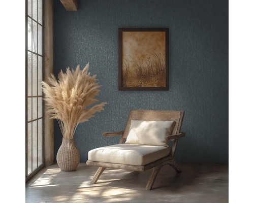 Rustikales Zimmer mit strukturierter Wand, Holzstuhl mit Rattangeflecht, Vase mit Pampasgras und gerahmtem Bild in hellem Tageslicht.