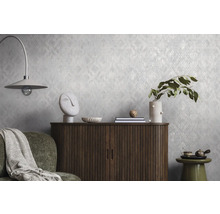 Strukturierte Vliestapete mit dezentem Muster an einer Wand hinter einer Holzkommode und Dekoration in einem modern eingerichteten Wohnraum.