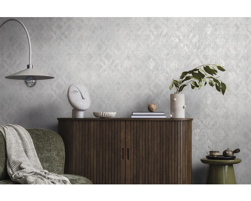 Strukturierte Vliestapete mit dezentem Muster an einer Wand hinter einer Holzkommode und Dekoration in einem modern eingerichteten Wohnraum.