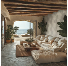 Rustikales Wohnzimmer mit großem Modulsofa, Holzdeckenbalken, Natursteinboden und Meerblick durch eine Rundbogenöffnung.