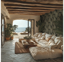 Helles Wohnzimmer im mediterranen Stil mit großem Sofa, Holzbalkendecke, Natursteinboden, Blättermuster-Tapete und Blick auf das Meer.