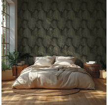 Schlafzimmer mit dunkel gemusterter Tapete mit Blattmotiv, hellem Bett, geflochtenem Teppich, Holzboden und Zimmerpflanzen in hellem Licht.