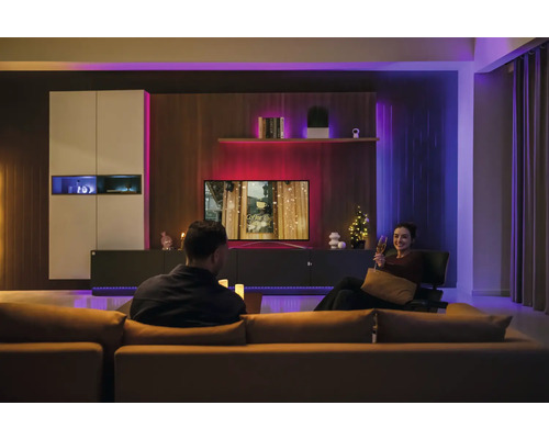 Modernes Wohnzimmer mit smarter LED-Ambientebeleuchtung hinter dem Fernseher und an den Möbeln für eine stimmungsvolle Atmosphäre.