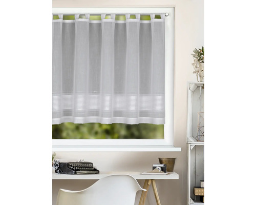 Weiße, halbtransparente Scheibengardine mit Schlaufen und Querstreifen an einem hellen Fenster über einem Schreibtisch mit Schreibmaschine.