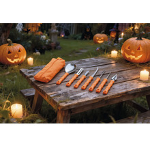 Siebenteiliges Kürbis-Schnitzset mit orangefarbenen Griffen und Tasche auf einem Holztisch mit beleuchteten Halloween-Kürbissen und Kerzen.