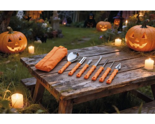 Siebenteiliges Kürbis-Schnitzset mit orangefarbenen Griffen und Tasche auf einem Holztisch mit beleuchteten Halloween-Kürbissen und Kerzen.