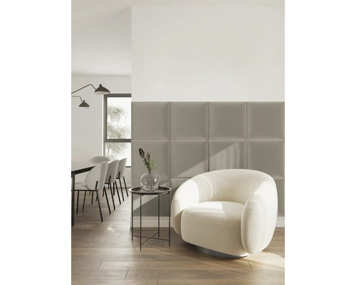 Quadratische Polsterpaneele an der Wand in einem modernen Wohnzimmer mit Bouclé Sessel und Beistelltisch auf Holzboden.