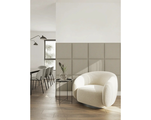 Helles Wohnzimmer mit quadratischen gepolsterten Wandpaneelen, einem runden Sessel mit Strukturstoff, Beistelltisch und Boden in Holzoptik.