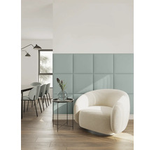 Modernes Wohnzimmer mit quadratischen Wandpaneelen, einem weißen Bouclé-Sessel, Beistelltisch mit Vase und Essbereich im Hintergrund.