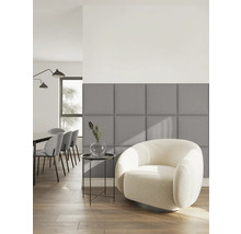 Modernes Wohnzimmer mit grauen quadratischen Polsterpaneelen an der Wand, einem weißen Sessel und einem Beistelltisch auf Holzboden.