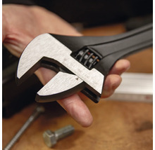 Verstellbarer Einmaulschlüssel aus schwarzem Metall mit silbernen Backen und Millimeterskala bis 40 Millimeter in einer Hand.