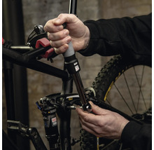 Eine Person verwendet einen Drehmomentschlüssel zur Einstellung von Schrauben an einem Mountainbike.