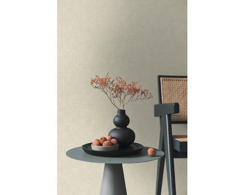 Strukturierte Vliestapete in Beige in einem modernen Wohnraum mit Beistelltisch, Vase mit Trockenblumen und Stuhl.