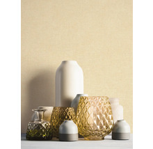 Feinstrukturierte Tapete in hellem Beige hinter einer Gruppe dekorativer Vasen aus Glas und Keramik.
