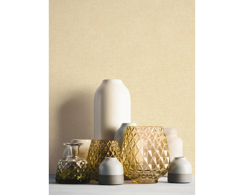 Feinstrukturierte Tapete in hellem Beige hinter einer Gruppe dekorativer Vasen aus Glas und Keramik.