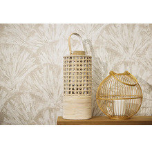 Zwei dekorative Windlichter aus Rattan und Holz auf einer Holzoberfläche vor einer gemusterten Tapete mit Fächermotiv.
