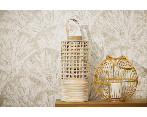 Zwei dekorative Windlichter aus Rattan und Holz auf einer Holzoberfläche vor einer gemusterten Tapete mit Fächermotiv.