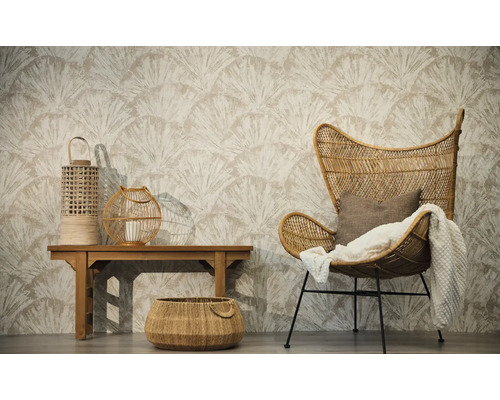 Wohnzimmer mit Vliestapete im Fächermuster, Rattansessel mit Kuscheldecke, Holzbank mit zwei Windlichtern und einem geflochtenen Bodenkorb.