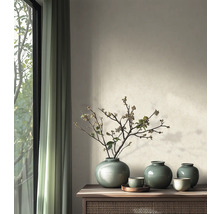 Helles Wohnzimmer mit hölzernem Sideboard, darauf grüne Keramikvasen mit Zweigen vor einer Wand mit strukturierter Farbe und Vorhängen.