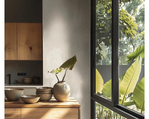 Helle, moderne Küche mit Holzschränken, Keramikschüsseln und Vase auf einer Holzfläche vor einem großen Fenster mit Blick auf grüne Pflanzen.