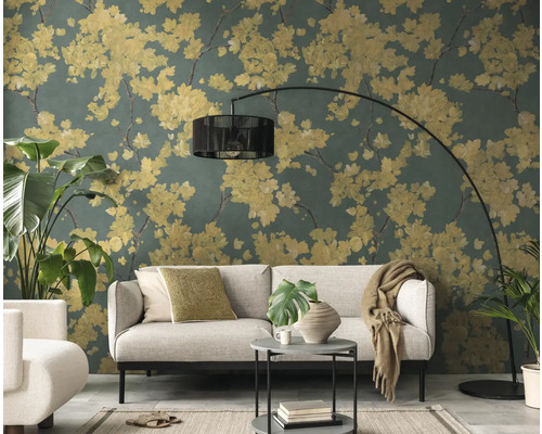 Wohnzimmer mit Vliestapete im floralen Muster, gelbe Blüten auf dunkelgrünem Hintergrund, hellgraues Sofa und schwarze Bogenlampe.