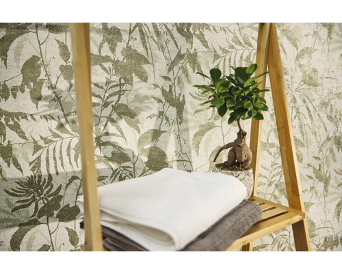 Vliestapete mit botanischem Blattmuster, davor ein Holzregal mit Handtüchern und einer Zimmerpflanze.