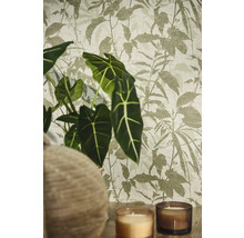 Vliestapete mit botanischem Blattmuster in wohnlicher Umgebung mit Alocasia Pflanze und Kerzen.