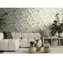Helles Wohnzimmer mit botanisch gemusterter Tapete, weißem Modulsofa, einem Glastisch mit Steinkugeln und verschiedenen Zimmerpflanzen.