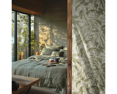 Schlafzimmer mit hellgrüner Leinenbettwäsche und Tapete mit botanischem Blattmuster vor einem sonnigen Fenster.