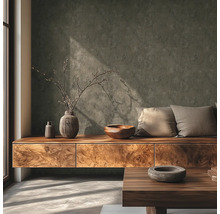 Modernes Wohnzimmer mit strukturierter dunkelgrauer Wand, Sideboard aus Holz, dekorativen Vasen, Holzschale und Kissen bei Tageslicht.
